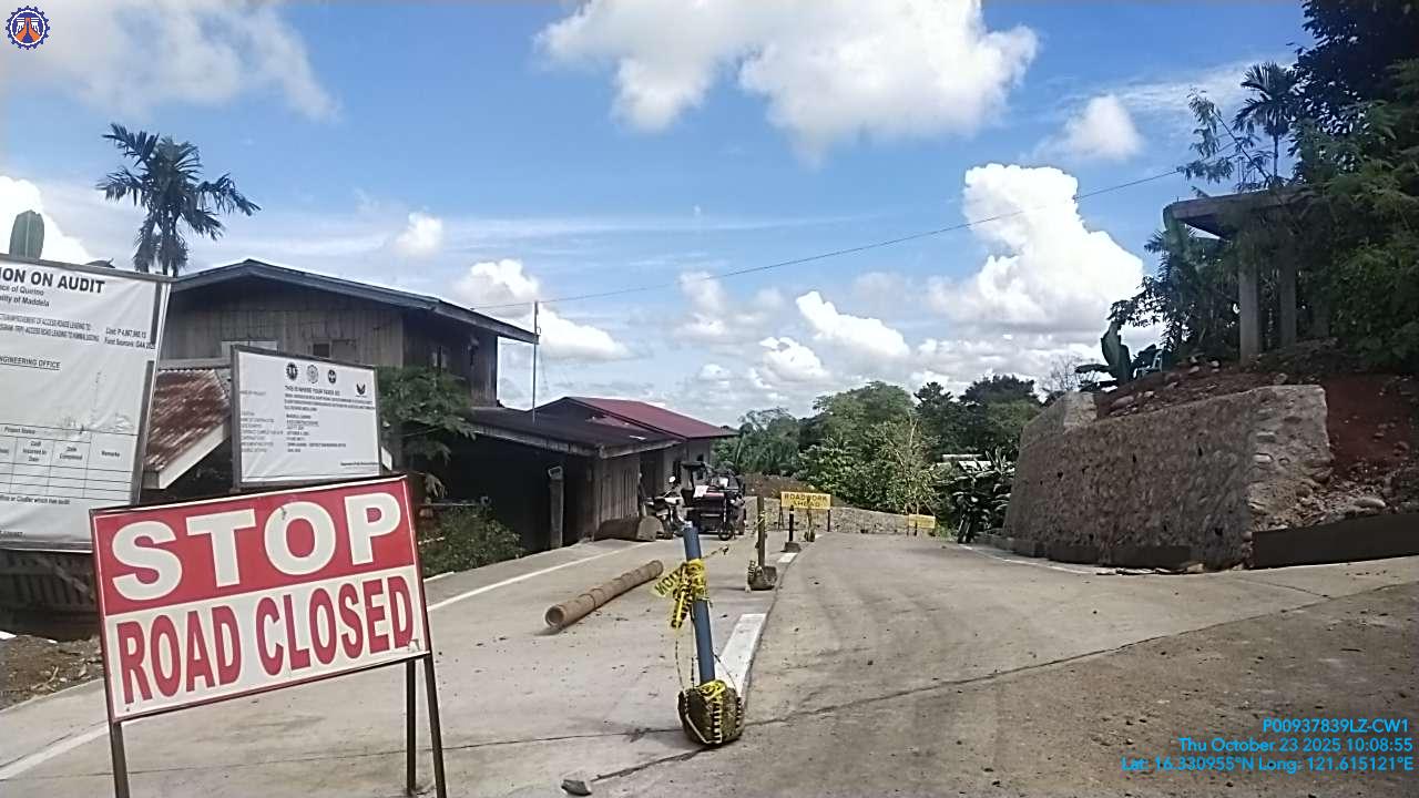 Concrete access road under construction with a STOP ROAD CLOSED sign and DPWH project billboards